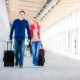 Man and woman walking through the airport pulling luggage