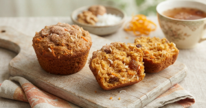 Homemade healthy carrot muffins with shredded coconut and raisins on a wooden board.
